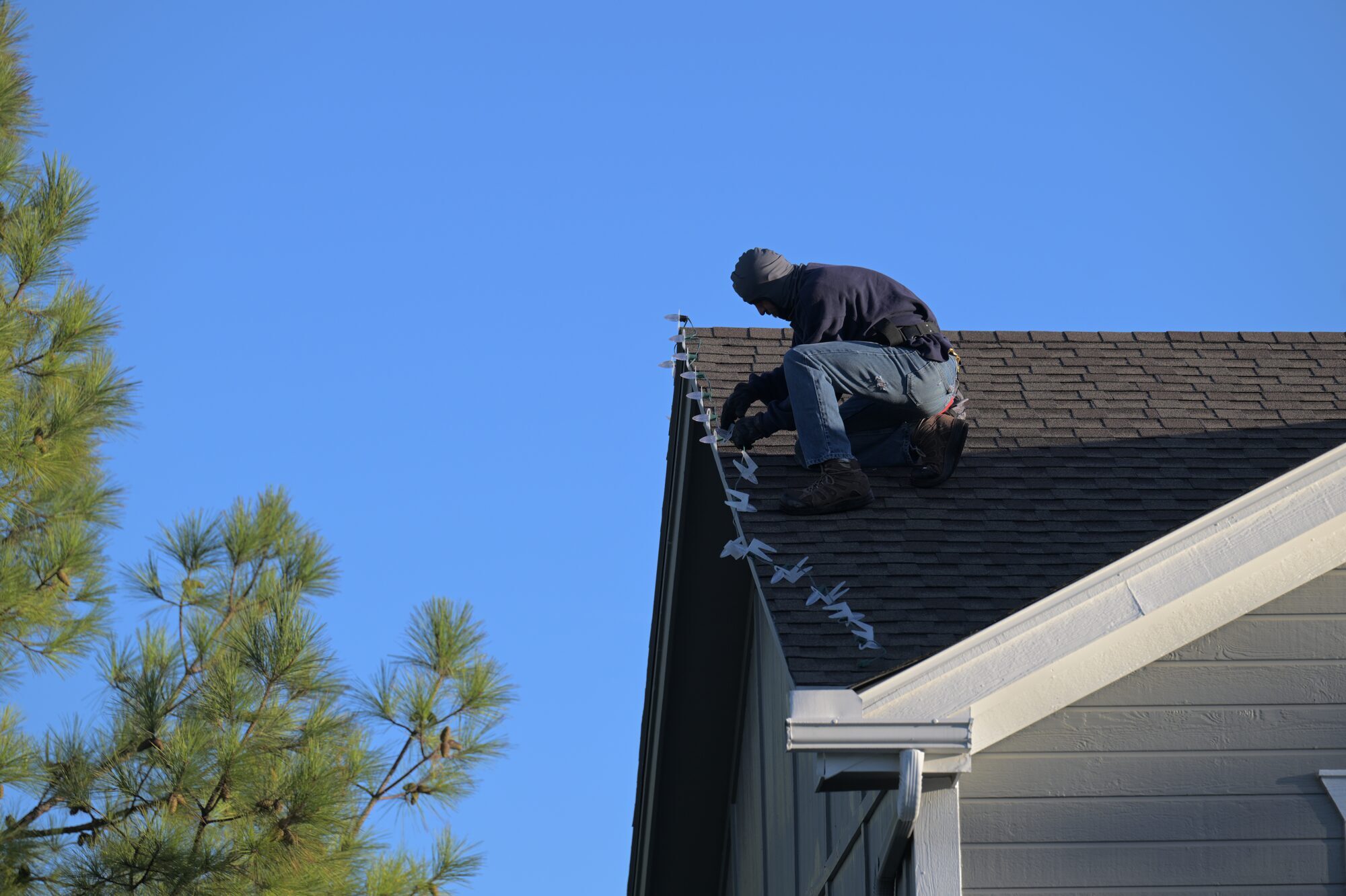 Reign Enterprises installer on roof clipping C9 sockets to roofline