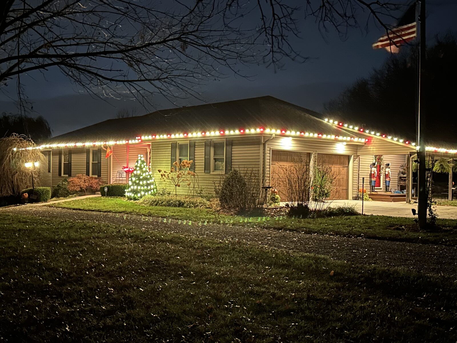 Multicolor C9 lights on ranch home with lit tree and nutcracker decorations