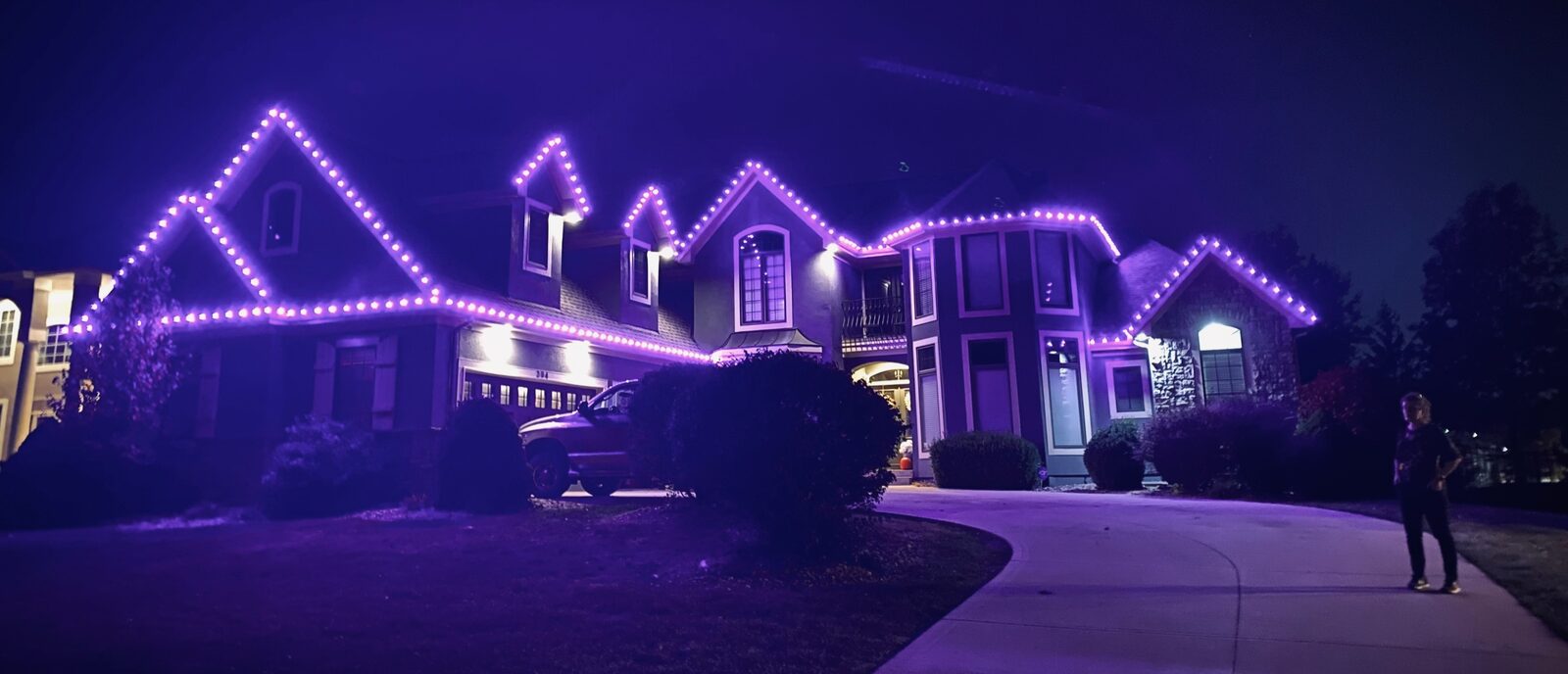 Purple violet C9 LED lights on large mansion roofline at night